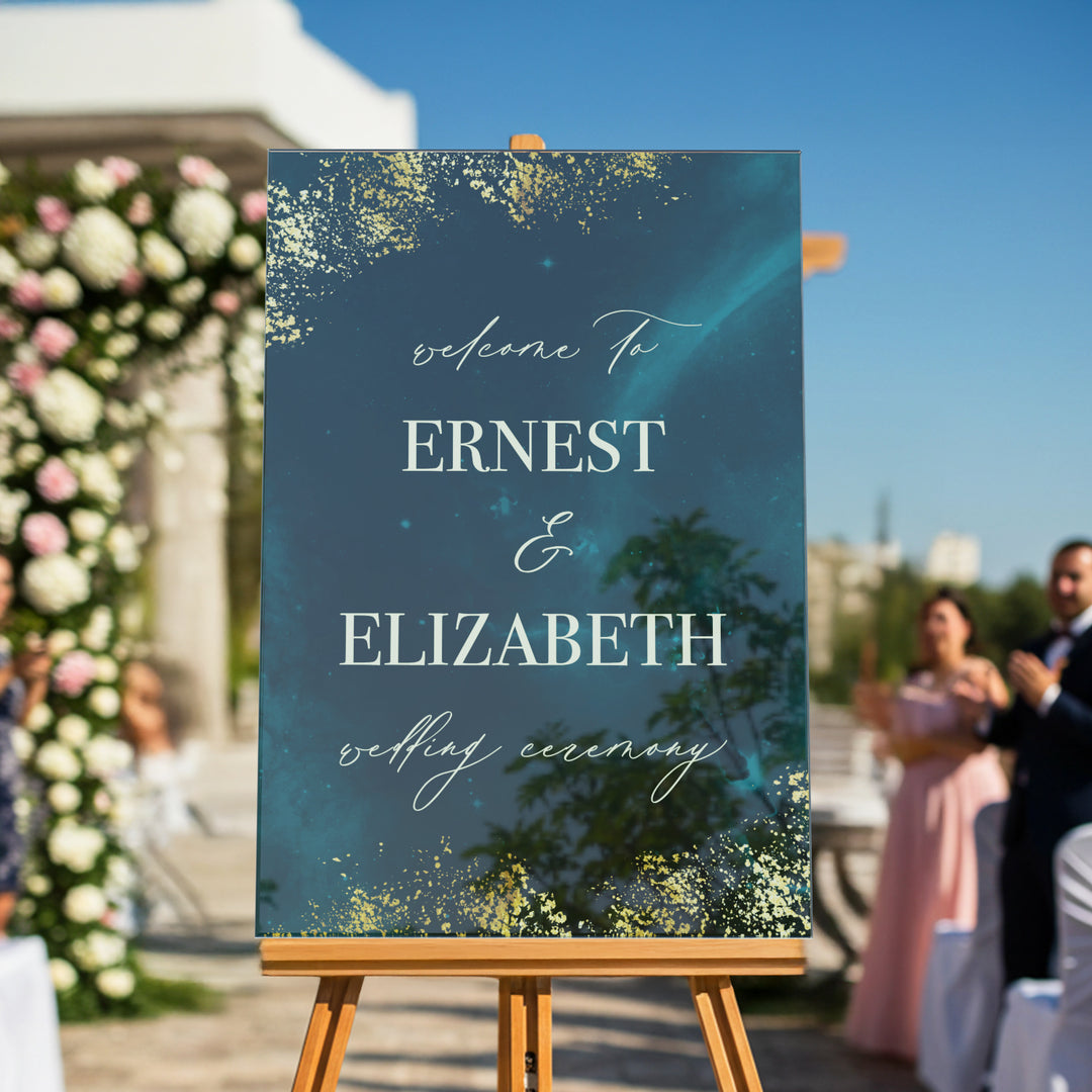 Wedding welcome sign on an easel with floral decorations and guests in the background