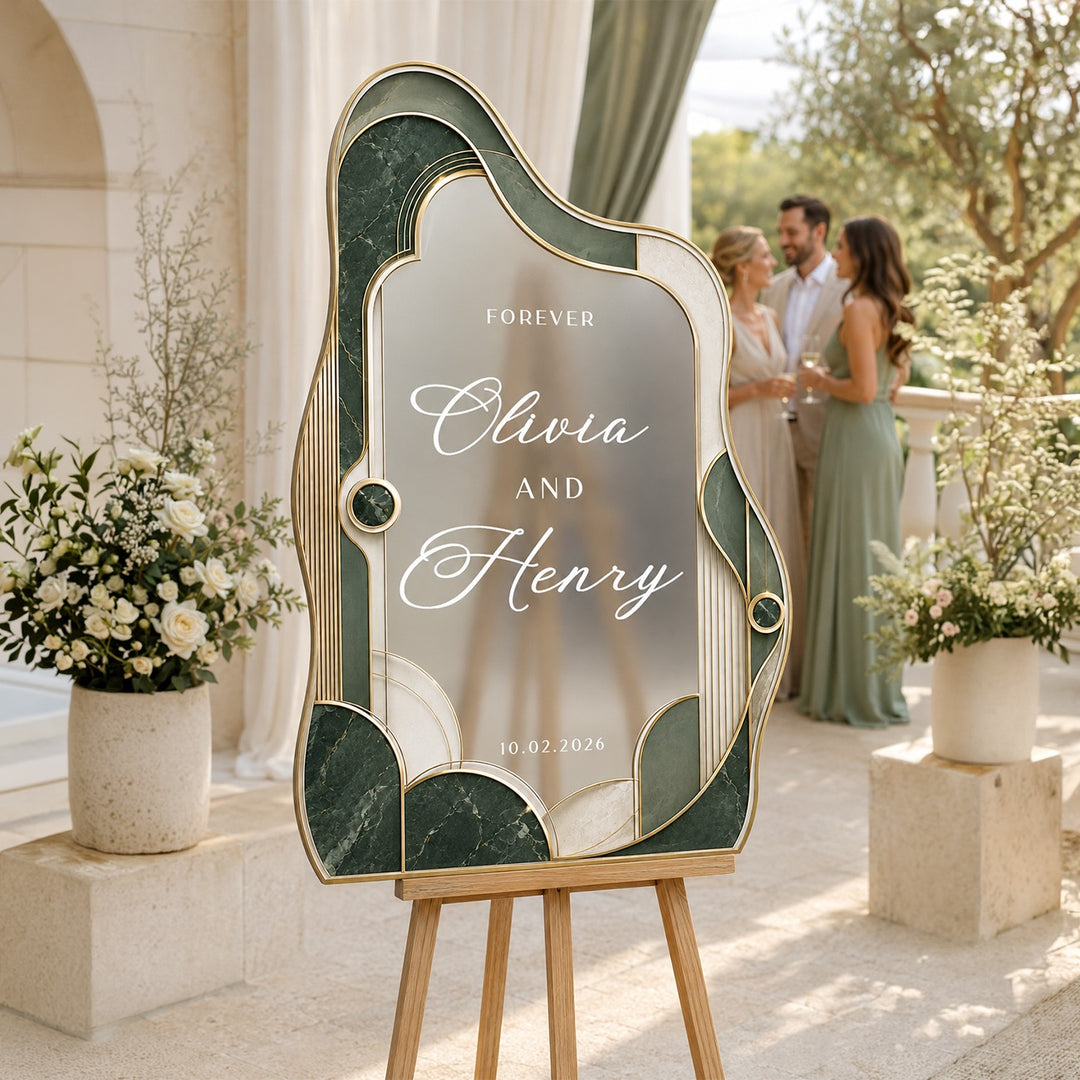 Emerald green wavy shape wedding welcome sign on easel with couple at outdoor estate ceremony.