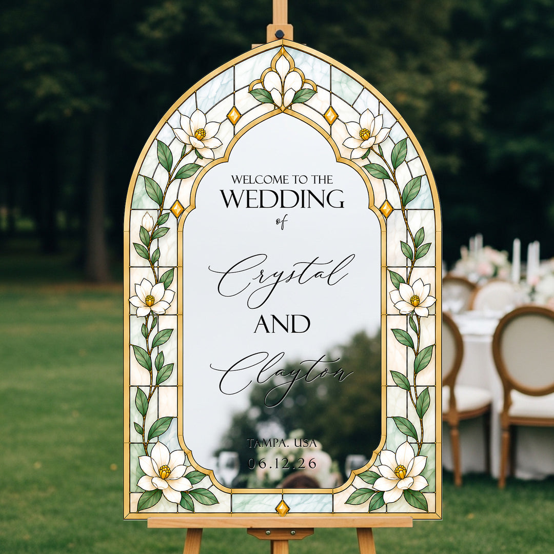 Decorative wedding sign with floral design and text on an easel outdoors.