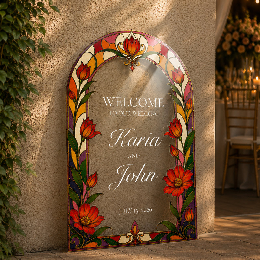 A decorative arched wedding welcome sign leaning against a beige stucco wall outdoors. The sign has a stained-glass-style floral border with red, orange, yellow, green, and purple flowers and leaves, and centered text. Red Tulip Folk Art Wedding Welcome Sign, clear acrylic sign.
