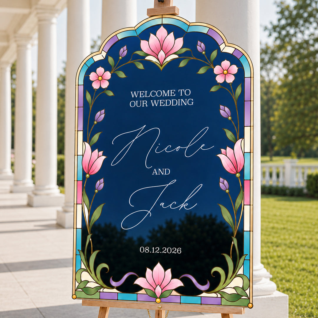 Pink lotus stained glass wedding welcome sign on easel — deep navy botanical arch at outdoor ceremony.