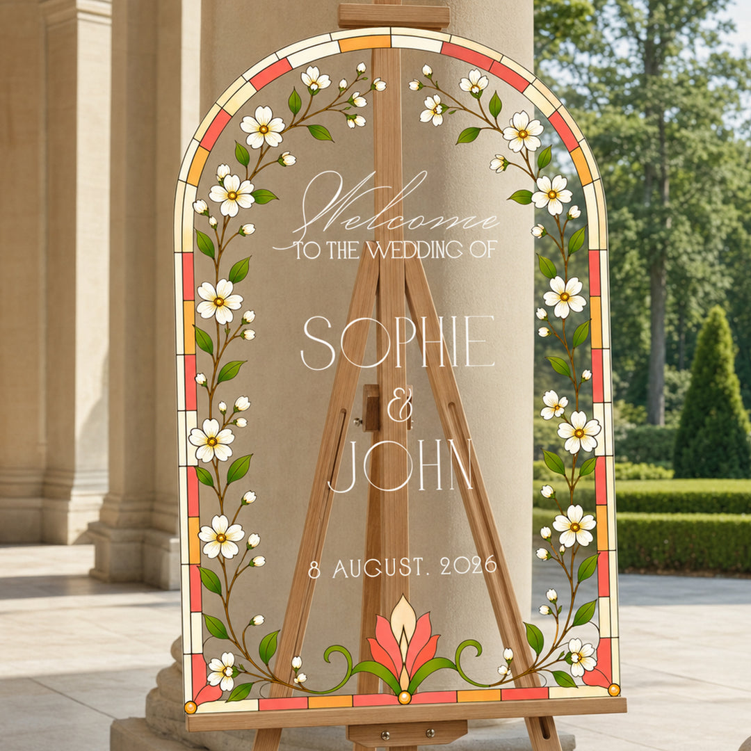 White tulip and daisy stained glass wedding welcome sign on easel at outdoor garden ceremony.